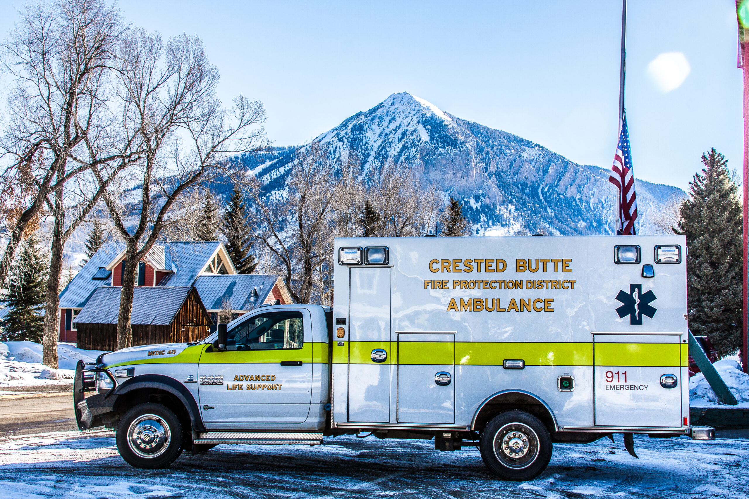 Photo of CBFPD Medic 45. White ambulance parked in front of a snow covered mountain.