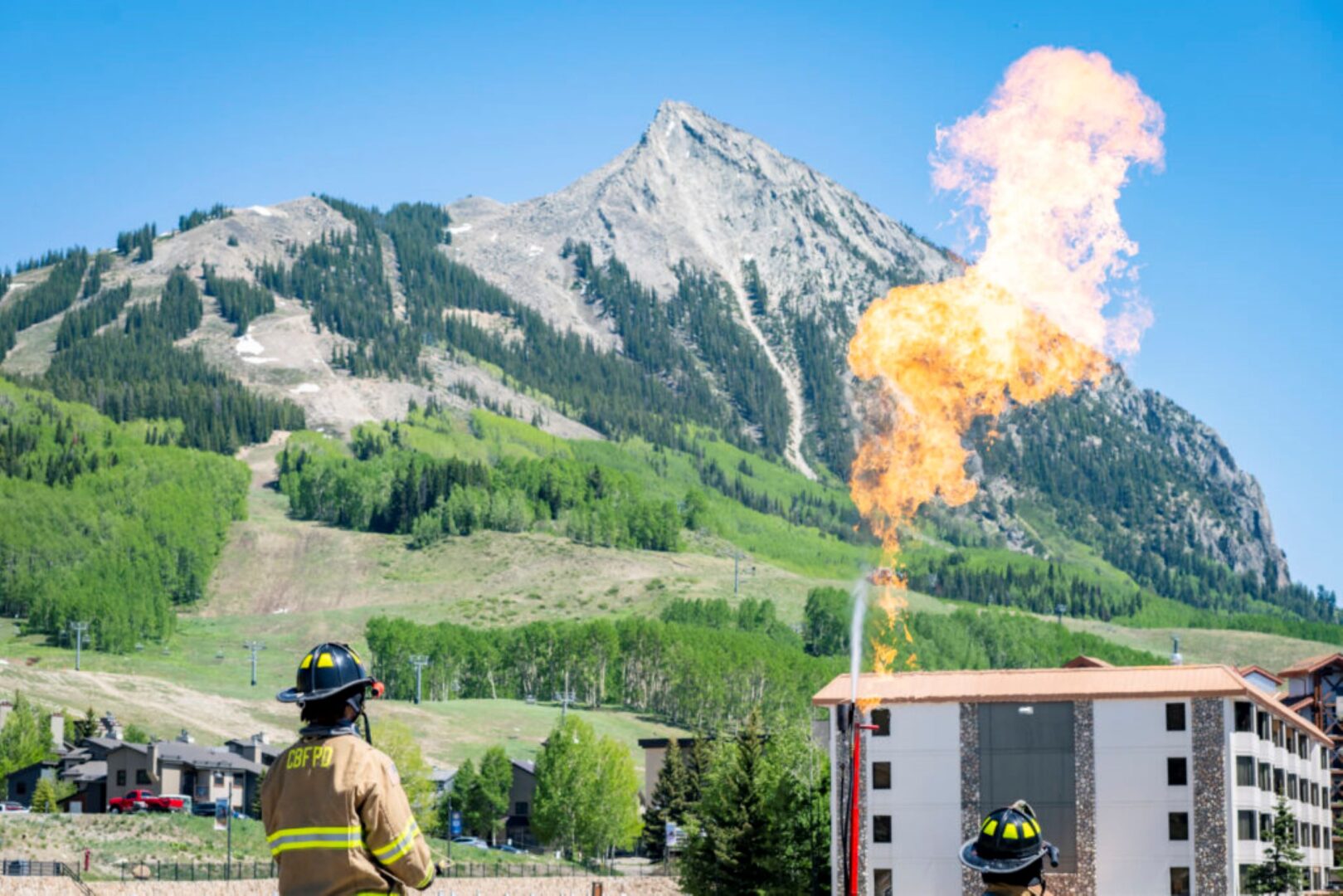 Propane Training photo with Mt. Crested Butte in the background, two firefighters and a propane flame in the foreground